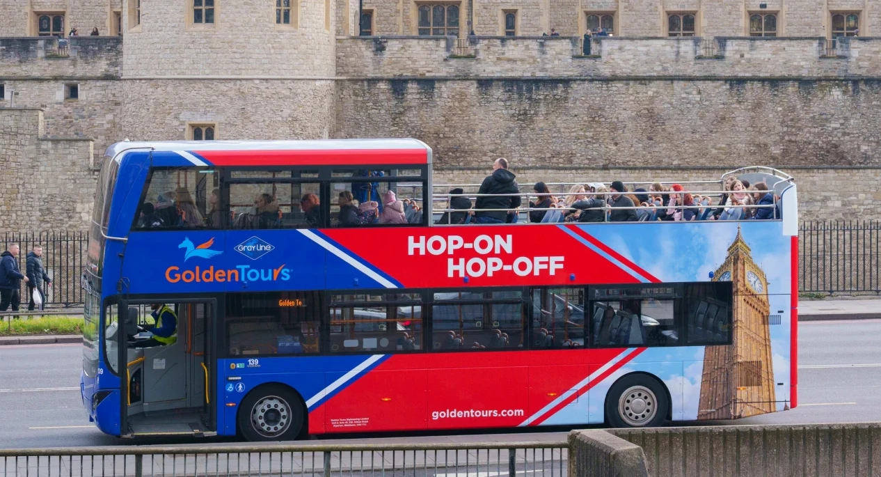 A photo of a Golden Tours hop-on hop-off bus driving past Westminster Abbey.