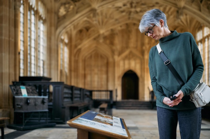 Close up person looking at old interpretation panel Divinity School