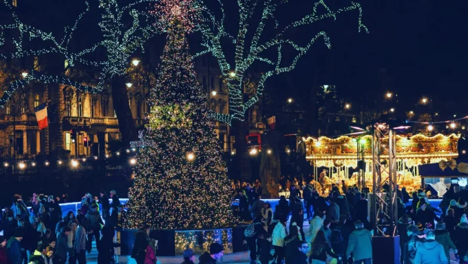 A photo of a decorated Christmas tree with people ice skating around it.