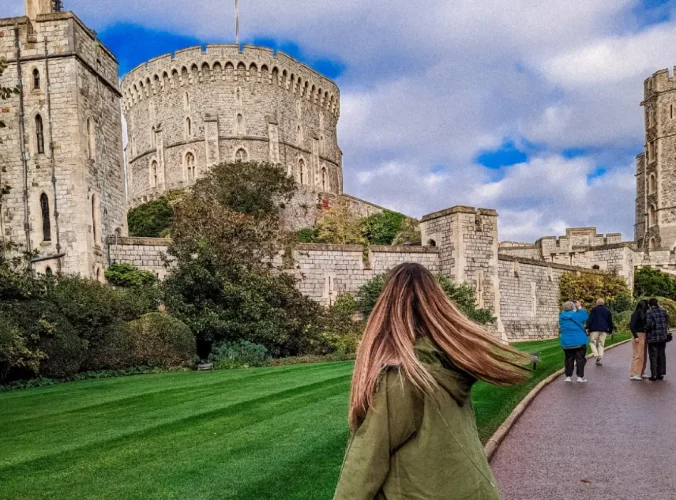 A photo of a woman in front of Windsor Castle.